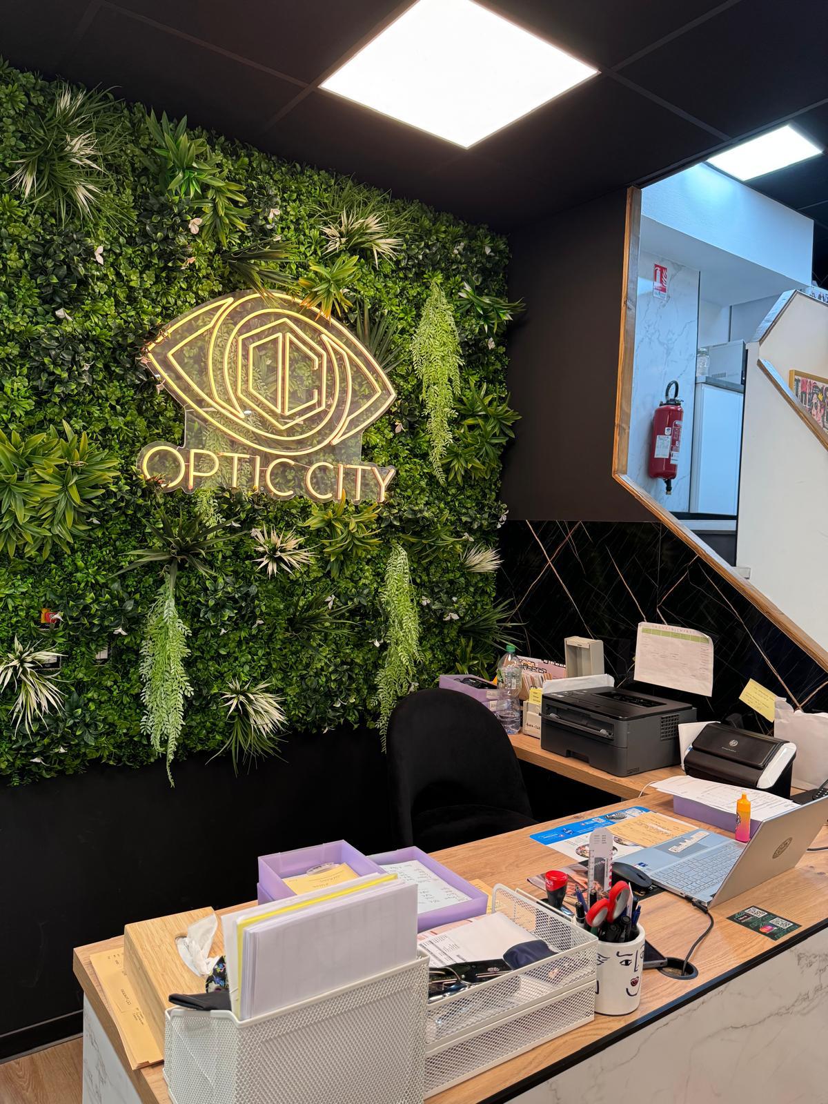 Le mur végétal et le logo néon doré Optic City à l'accueil de la boutique